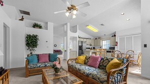 Ein geräumiges Wohnzimmer mit zwei Korbschaukelsofas, einem Glastisch und einem Deckenventilator.