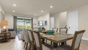 Un comedor con una mesa de vidrio, seis sillas y un cuenco decorativo.