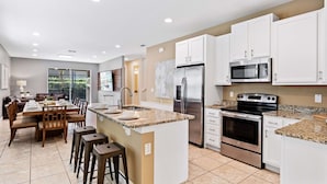 A modern kitchen with white cabinets, stainless steel appliances, and a granite countertop. - 25% Off 8BR Villa! Private Pool & Spa (Kissimmee)