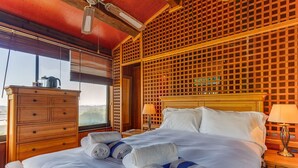 Ein Hotelzimmer mit einem großen Bett, einem Holzkopfteil und Blick durch ein Fenster.