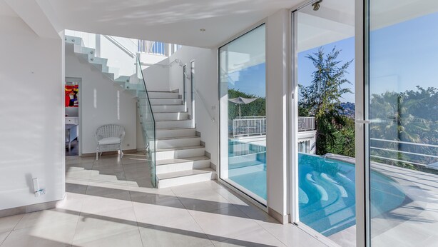 Ein modernes Interieur mit einer Glasstufen-Treppe, die zu einem Balkon mit einem Pool führt.