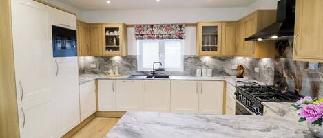 A modern kitchen with wooden cabinets, a marble countertop, and a black stove.