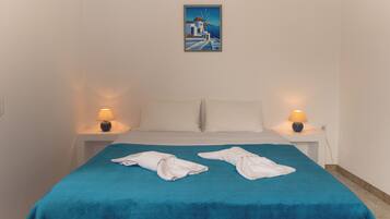 Quarto de hotel com uma cama, duas luminárias de cabeceira, um quadro na parede e duas toalhas sobre a cama.