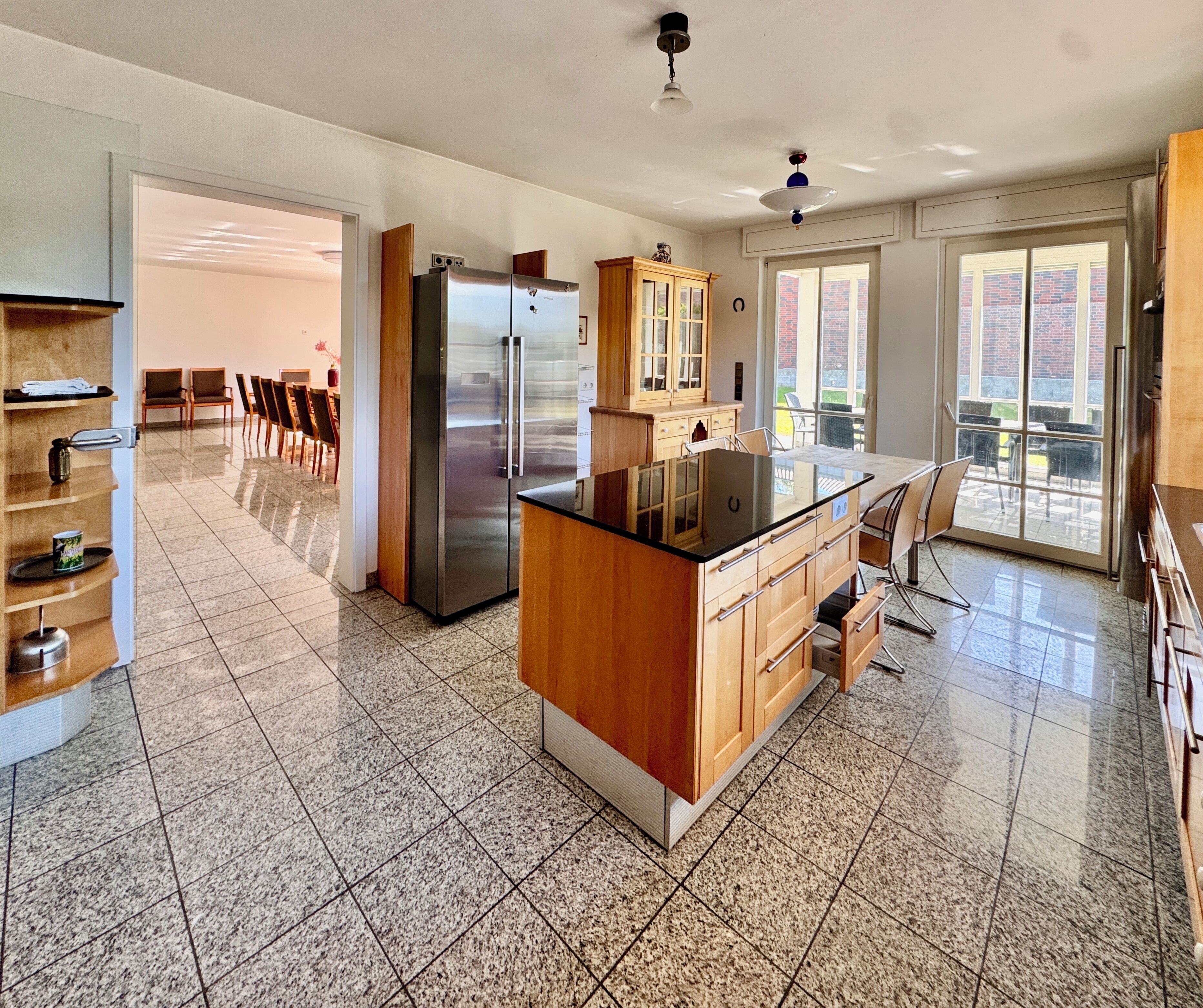 A modern kitchen with a central island, stainless steel appliances, and a dining area with chairs.