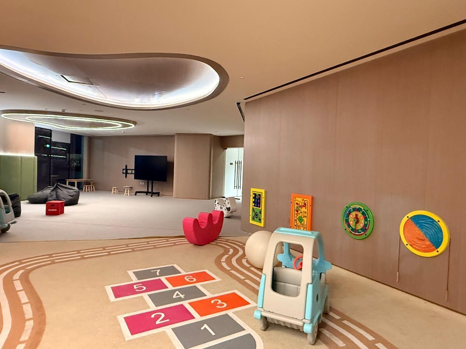 Una stanza moderna con un gioco dell'oca, una piccola macchinina e giocattoli didattici appesi al muro.