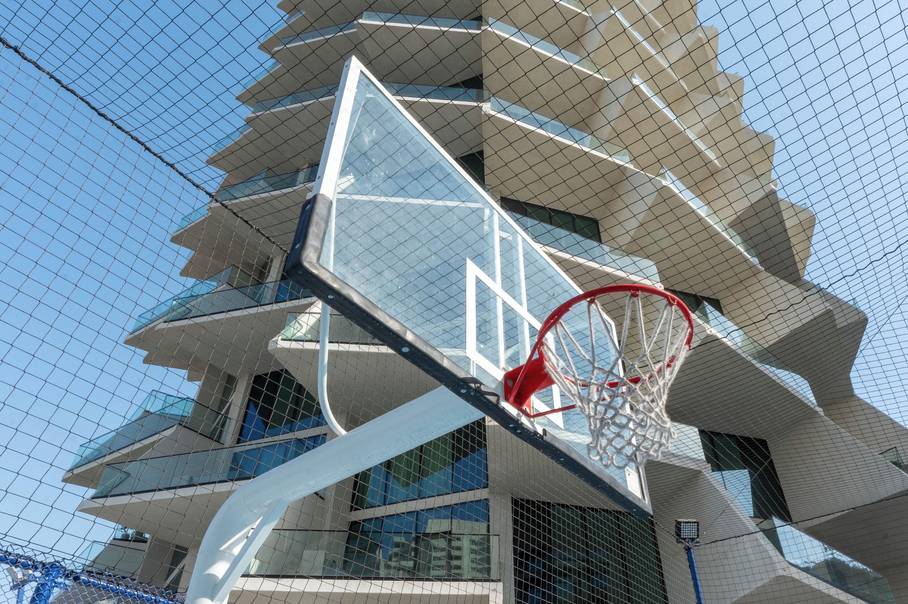 A basketball hoop attached to a modern building with a unique geometric design.