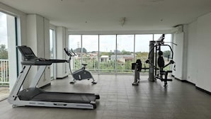 A gym with a treadmill, elliptical, and weight machines. - Apartemen Poris 88 by Linkara (Tangerang)