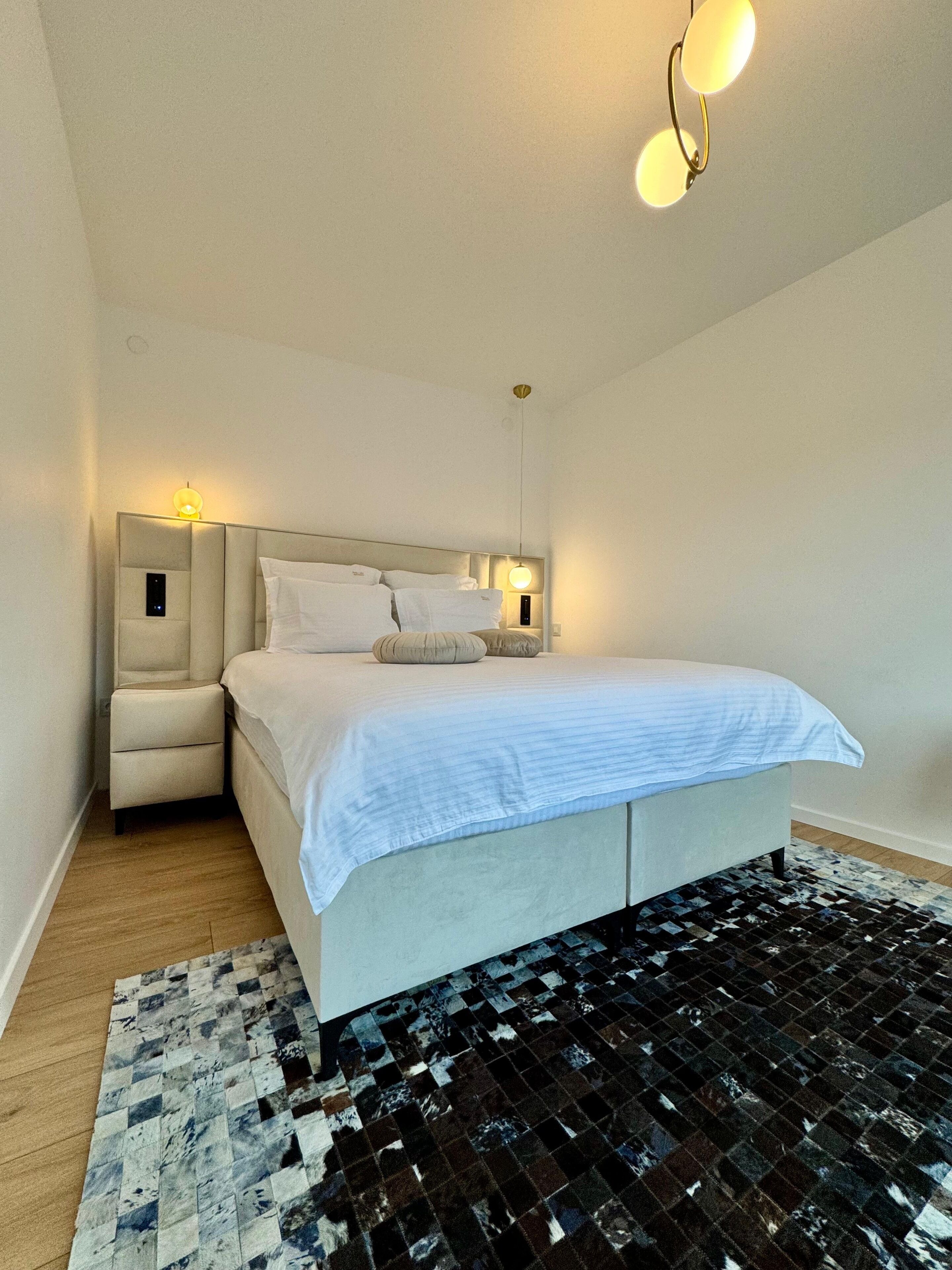 Ein modernes Schlafzimmer mit einem großen Bett, Nachttischen inklusive Lampen und einem gemusterten Teppich.