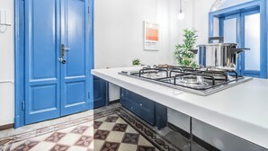 Une cuisine avec un plan de travail blanc, des portes bleues et un sol carrelé.