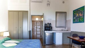 Een slaapkamer met een bed, een bureau, een magnetron en een kleine kitchenette.