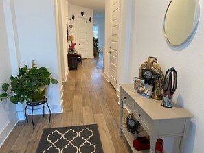 Ein Flur mit einem Blumentopf, einem Konsolentisch mit Dekoration und einem gemusterten Teppich.