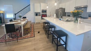 A modern kitchen with white cabinets, a large island, and pendant lighting. - Large 5-Bedroom Georgetown Getaway/Minutes to Blue Hole Park + Historic Square (Georgetown)