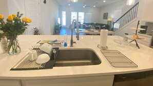 A modern kitchen with a large island, stainless steel sink, and pendant lighting. - Large 5-Bedroom Georgetown Getaway/Minutes to Blue Hole Park + Historic Square (Georgetown)