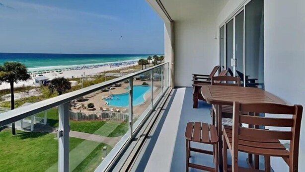 Un balcon avec vue sur une plage et une piscine.