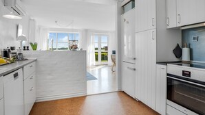 A modern kitchen with white cabinetry, a built-in oven, and a view to the outside. - "Jurien" - 50m to the fjord by Interhome (Snedsted)