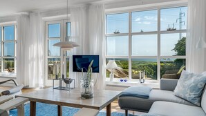 A modern living room with a large TV, comfortable seating, and a view of the sea and power lines. - "Jurien" - 50m to the fjord by Interhome (Snedsted)