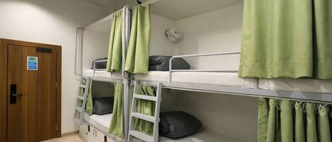 A bunk bed room with green curtains, a wooden door, and a white wall.
