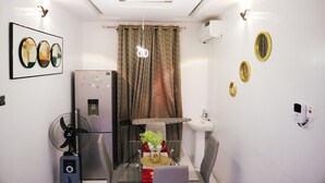 A compact kitchen with a refrigerator, sink, and a fan. - UTL Homes & Apartments
Brighton Apartment (Ibadan)
