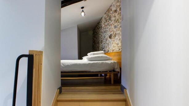 A narrow staircase leading to a bed with white bedding and a wooden headboard. - Le Léo Lagrange de Foix (Foix)