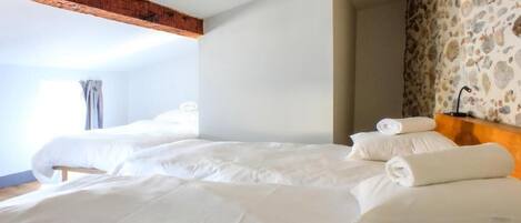 Una habitación de hotel con una cama grande, cabecera de madera y pared con diseño de piedra.