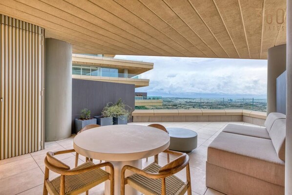 A modern outdoor seating area with a round table and chairs, a sofa, and potted plants. - Stylish Studio • Terrace & Open Views (Rabat)