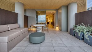 A modern outdoor seating area with a sofa, round table, and chairs, leading to an interior space with a view. - Stylish Studio • Terrace & Open Views (Rabat)