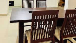 A dining area with a rectangular table and four wooden chairs with cushioned seats. - 2BHK Apartment near Guruvayur Temple (Guruvayur)