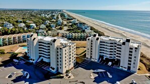 Un hôtel situé sur la côte, composé de plusieurs bâtiments, doté d’aires de stationnement et offrant une vue sur la plage.