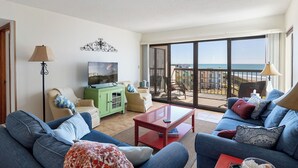 Un salon doté d’une grande porte-fenêtre coulissante donnant sur un balcon avec vue sur la mer.