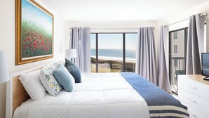Une chambre d’hôtel avec un lit, un tableau, un bureau et une vue sur la plage.