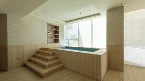 Ein modernes Interieur mit integriertem Pool, Holzstufen und großen Fenstern.