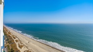 Une plage d’où l’on a une vue dégagée sur l’océan, avec un bâtiment situé sur la gauche.
