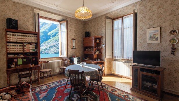 Ein gemütliches Wohnzimmer mit großem Fenster, einem Esstisch und einem Fernseher.