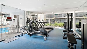 Un gimnasio moderno con equipo de cardio, máquinas de pesas y una zona de piscina.