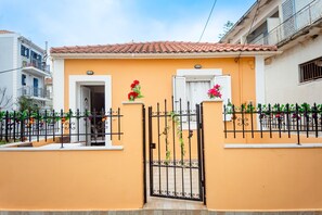 A residential building with a tiled roof, a gated entrance, and flower arrangements on the gate. - Spacious 2 Bd Detached House in Kefalonia w Patio (Lixouri)