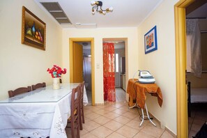 A dining area with a glass table, chairs, a vase with flowers, and a painting on the wall. - Spacious 2 Bd Detached House in Kefalonia w Patio (Lixouri)