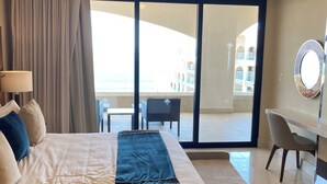 A hotel room with a large bed, a desk, a chair, and a view of the building outside. - Charming 2BR Resort suites in enchanting San José del Cabo tourist Corridor (San José del cabo)