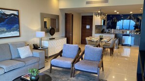 A modern living room with a sofa, armchairs, a coffee table, and a dining area with a table set for four. - Charming 2BR Resort suites in enchanting San José del Cabo tourist Corridor (San José del cabo)
