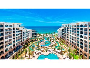 A resort with multiple swimming pools, palm trees, and a view of the ocean. - Charming 2BR Resort suites in enchanting San José del Cabo tourist Corridor (San José del cabo)
