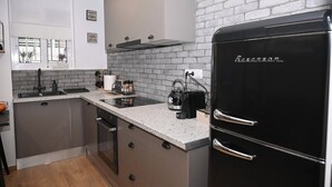 A compact kitchen with a black refrigerator, a built-in oven, and a granite countertop. - Urban Loft by Neuvel (Athens)