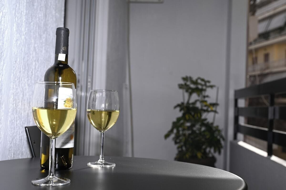 Een fles wijn en twee glazen op een tafel, met een bloempot in de achtergrond.