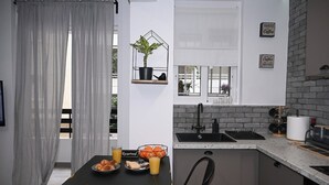 A compact kitchen with a dining area, a potted plant on a shelf, and a sign reading "POWERED Coffee". - Urban Loft by Neuvel (Athens)