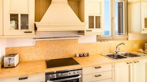 Una cocina con gabinetes de madera, un lavamanos de acero inoxidable, un tostador y una estufa.