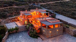 Una casa moderna de varios niveles con fachada de piedra, numerosas ventanas y un patio empedrado.