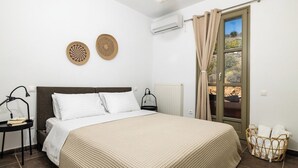 Un dormitorio con cama, mesita de noche, lámpara, ventana con cortinas y vistas al exterior.