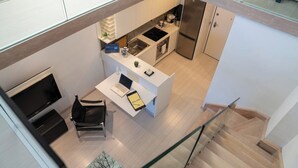 Una cocina moderna con horno empotrado, refrigerador y comedor con una silla y mesa.