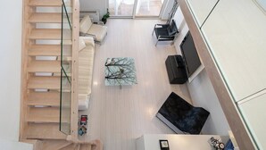 Un interior moderno con una escalera, un sofá, una mesa de centro y un televisor.