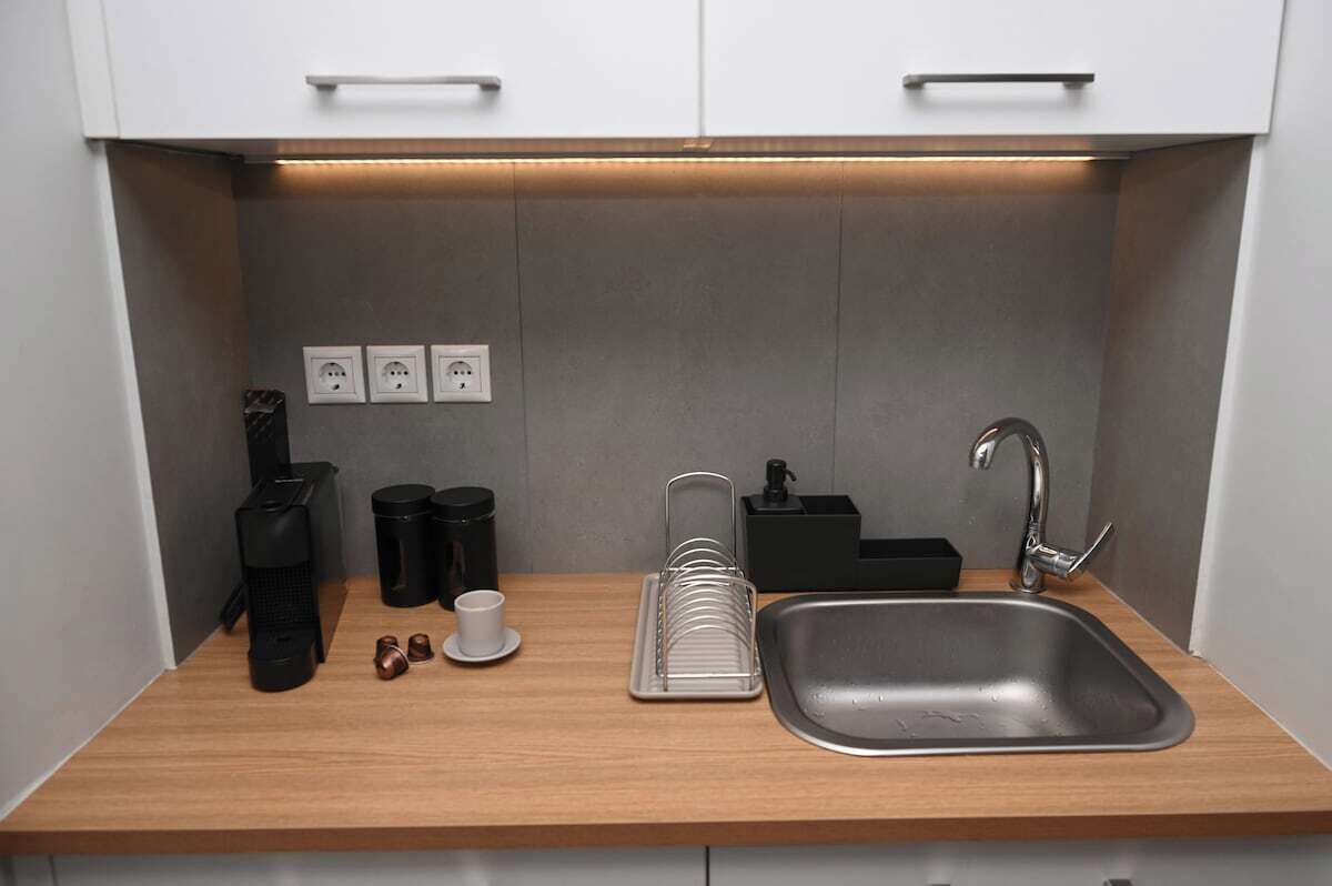 Cocina compacta con un lavamanos, encimera y tres enchufes.
