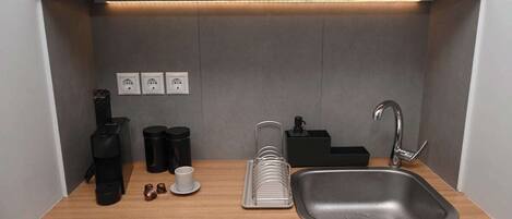 Cocina compacta con un lavamanos, encimera y tres enchufes.