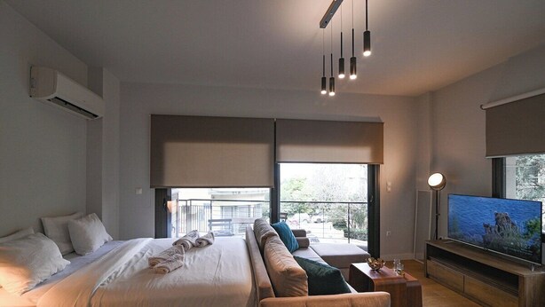 Una camera d'albergo moderna con un letto grande, un divano, una TV e un balcone con vista.
